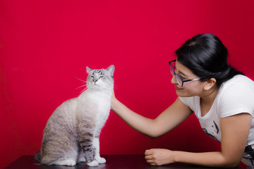 Mujer cabello negro lacio acariciando mascota gato siamés