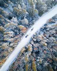 Aerial view of snow covered forest and road with cars.