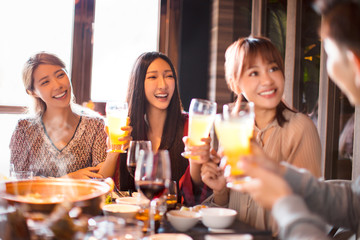 happy young friends eating hot pot in restaurant