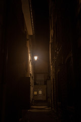 Dark street, an impasse in a dead end back street, with a dim orange light, surrounded by...