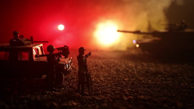 War Concept. Military silhouettes fighting scene on war foggy sky background at night. Armored vehicles with soldiers ready to attack. Artwork decoration. Selective focus