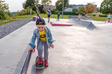 Playground children play skate, little boy 3-5 years old, learning skate, scooter board skateboard, handrail. In summer, in fall, having fun, resting on weekend, free space for text.