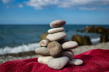 stones stacked pyramid on the beach against blue sky and sea.