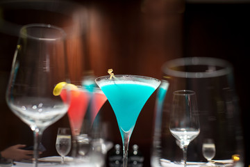 blue cocktail in selective focus over the other glasses for abstract mood