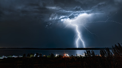 Lightning strike in the night sky above the river