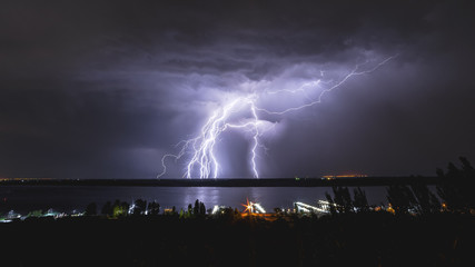 A bright flash of lightning in the sky above the river