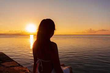 夕日を見る女性　沖縄　竹富島の西桟橋