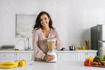 happy pregnant woman standing near blender with smoothie