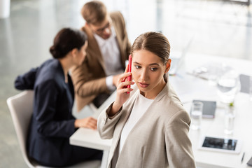businesswoman in formal wear talking on smartphone in office
