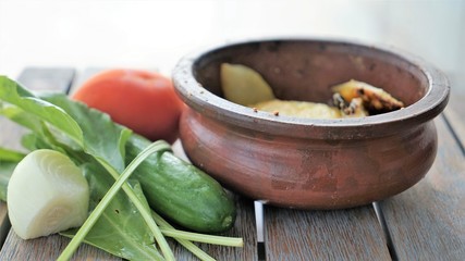 vegetable soup in pottery and green salad on wooden surface