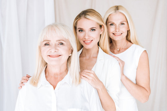 happy elegant three-generation blonde women in total white outfits