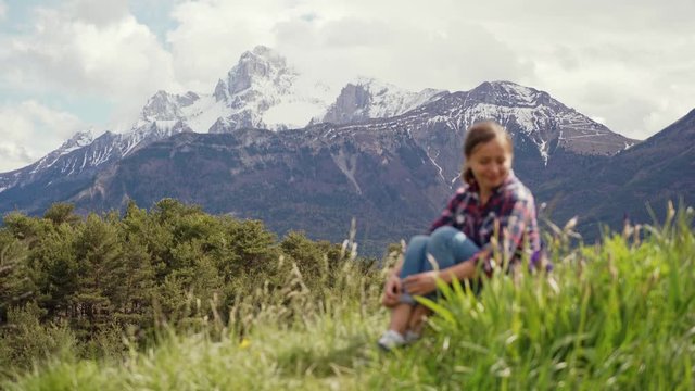 Beautiful view of Alps mountains and blurred image of tourist woman sitting on a green meadow. Travel in Alps mountains