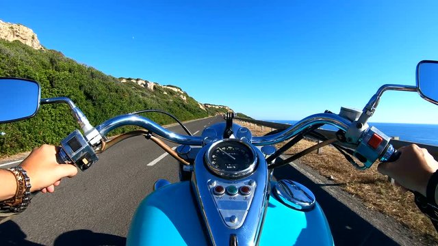 Motorcycle ride on a winding coastal road at sunset. Sardinia, Italy