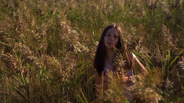 Funny girl portrait on reed field in slow motion.