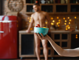 Nude young husband poses on the kitchen