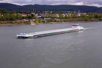 Ship, barge (tanker freighter) on the river Rhine in mountain or descent in late summer under cloudy sky..