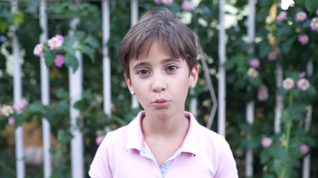 Eight years old girl smiling and blowing a kiss outdoors