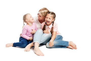 Mom and daughters are sitting and laughing. Love and tenderness. Isolated over white background.