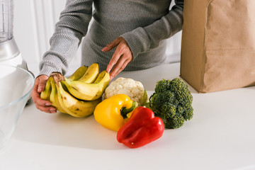 cropped view of girl touching bananas near vegetables