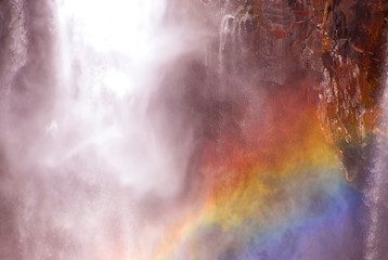 絶壁から流れ落ちる滝に虹が出来た光景をクローズアップ