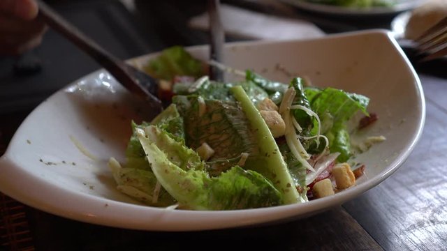 Hands mixing caesar salad