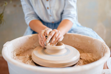Female potter making a pot on pottery wheel