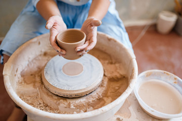 Fototapeta na wymiar Female master holds wet pot over the pottery wheel