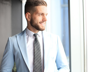Fototapeta premium Modern business man in formalwear standing near window in the office