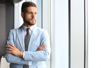 Portrait of happy businessman with arms crossed standing in office