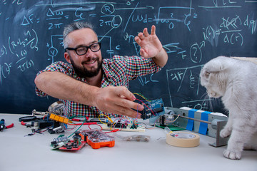 Hipster guy working on arduino project getting visited by cat