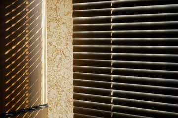Light through the blinds. The morning sun illuminates through the blinds a wooden vertical surface leaving a beautiful pattern of shadows. Dark brown tonality.