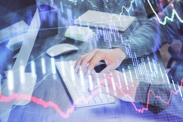 Stock graph with businessman typing on computer in office on background. Concept of analysis. Double exposure.