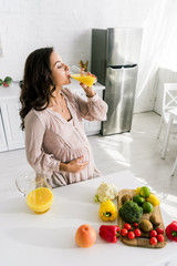 attractive pregnant woman drinking fresh orange juice