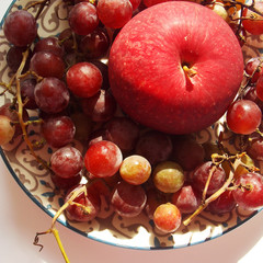 red apple with grapes. on top of the macro. background