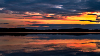 Fototapeta na wymiar Water reflections at midnight sun at serene lake in finlandd