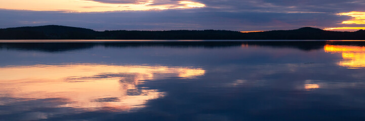Water reflections at midnight sun at serene lake in finlandd