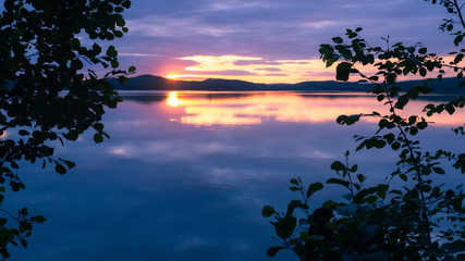 Water reflections at midnight sun at serene lake in finlandd