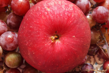 red apple with grapes. on top of the macro. background