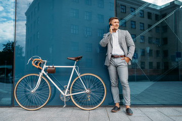 Businessman talking by mobile phone at the bicycle