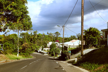 Dramatic sky over road through Caribbean dwellings of Guadeloupe (France)