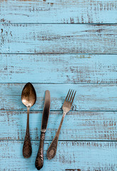Vintage cutlery - spoons, forks and knives on an old wooden background.