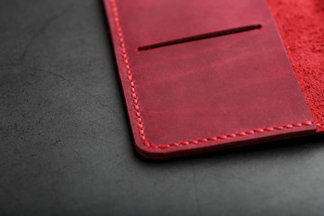 Red leather cover for a passport on a dark background. Genuine leather, handmade, close up stitching