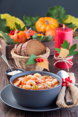 Soup with turkey, pasta, carrot, celery, tomato and cannellini beans on the table with autumn decoration, reflecting the US Thanksgiving harvest feast, vertical