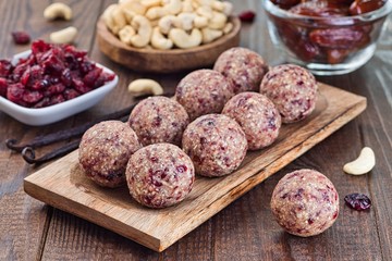 Healthy homemade energy balls with cranberries, cashew nuts, dates and vanilla on a wooden plate, horizontal