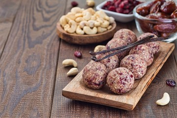 Healthy homemade energy balls with cranberries, cashew nuts, dates and vanilla on a wooden plate, horizontal, copy space