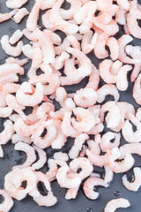 Frozen raw peeled shrimps on a dark background, vertical,  top view