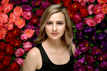Naklejka premium Portrait of a pretty young blonde girl with beautiful hair, excellent make-up, beautiful face skin in a black blouse on a colored background. Made in the studio.