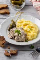 Beef Stroganoff, traditional Russian dish of goulash with beef in creamy sauce, mashed potatoes and pickles. Serve with rustic bread