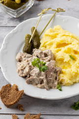 Beef Stroganoff, traditional Russian dish of goulash with beef in creamy sauce, mashed potatoes and pickles. Serve with rustic bread