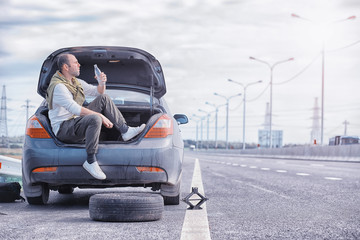 Replacing the wheel of a car on the road. A man doing tire work on the sidelines.